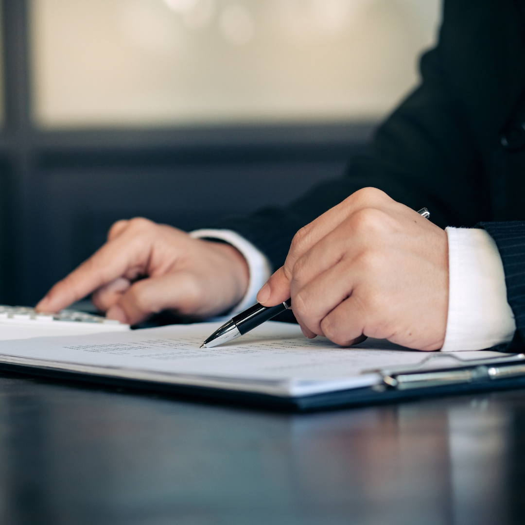Healthy Home & Office - Person's hands with a pen and paper on a desk, blurred background