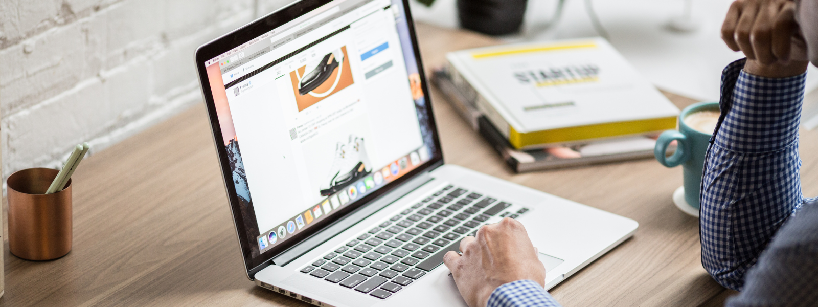 Healthy Home & Office - Person using a laptop on a desk with a book and mug in the background
